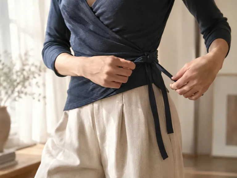 Hände binden die seitliche Bindung eines marineblauen Jersey-Wickeltops